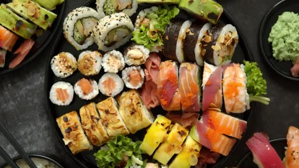 Asian food fest. Menu sushi with nigiri, maki, uramaki on black plates. Various kinds of sushi — Stock Video