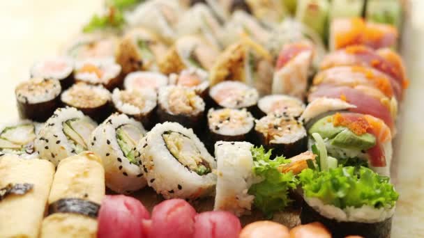 Horní pohled na pozadí se sadou barevných různých druhů sushi rolí umístěných na dřevěné desce — Stock video