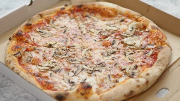 Een pizzadoos. Gehakte hete pizza in een kartonnen doos. Pizza met champignons en kaas. — Stockvideo