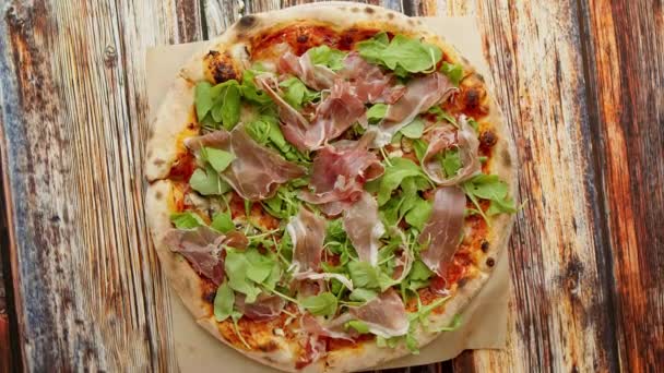 Pyszne domowe włoskie prosciutto i pizza rukola umieszczone na drewnianym tle — Wideo stockowe