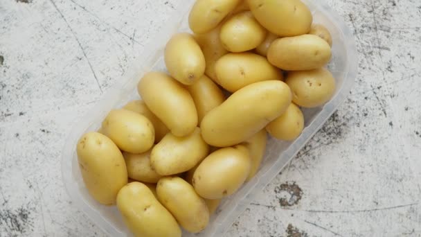 Νεαρές πατάτες σε πλαστικό καλάθι τοποθετημένες σε λευκό σκουριασμένο φόντο — Αρχείο Βίντεο