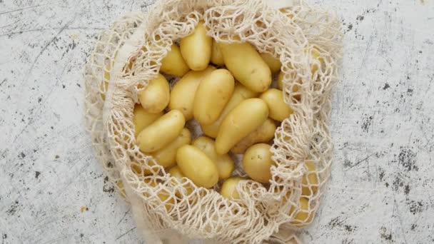 Patate fresche giovani in una borsa ecologica a rete zero rifiuti posta su sfondo bianco graffiato — Video Stock