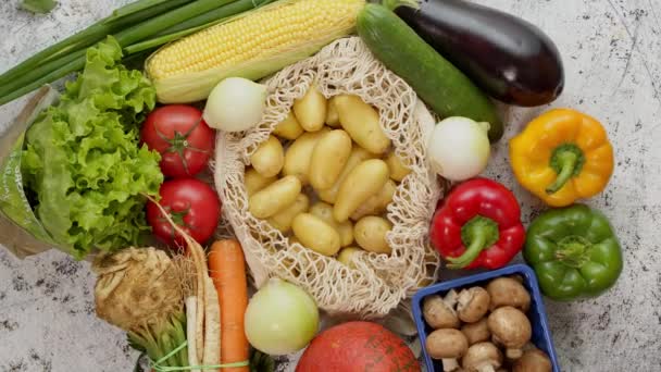 Zöldségek újrahasznosítható hálós zsákokban, fehér karcos háttérrel, felülnézetből. Zéró hulladék és ökohulladék — Stock videók