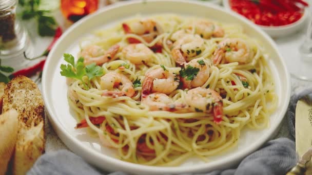Spagetti garnélarákkal fehér kerámia tányéron, és egy pohár fehérborral tálalva — Stock videók