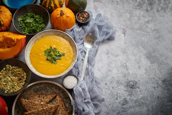 Soupe de citrouille décorée de persil pour Thanksgiving, Halloween. Placé sur fond de pierre grise — Photo