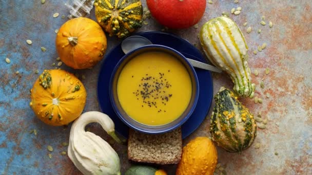 Compositon with autumn classic food. Tasty homemade pumpkin soup decorated with black seed — Stock Video