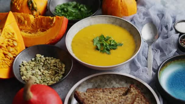 Pumpkin soup decorated with parsley for Thanksgiving, halloween. Placed on grey stone background — Stock Video
