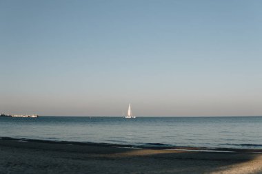 Sahil manzarası ve gün sonunda sakin denizde yelken açan gemiler.