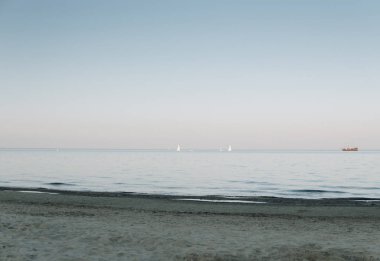 Sahil manzarası ve gün sonunda sakin denizde yelken açan gemiler.