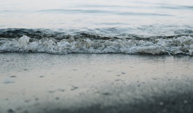 Küçük dalgaların kumlu bir kıyıya vuruşunun yatay görüntüsü