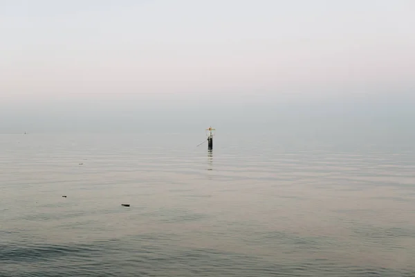 日没時に穏やかな海の上の憂うつな海のシングルブイ — ストック写真