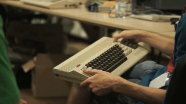 Klavye ile eski bilgisayar tutan ve retro makineleri hakkında konuşurken insanların yanında kamera slayt