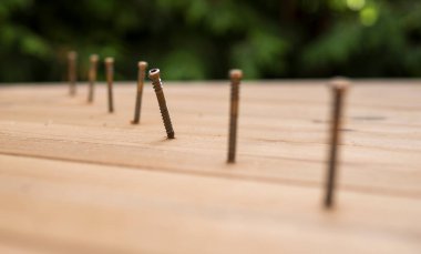 Ahşap terasın yapımı sırasında bir sıra metal vidayı kapatın.
