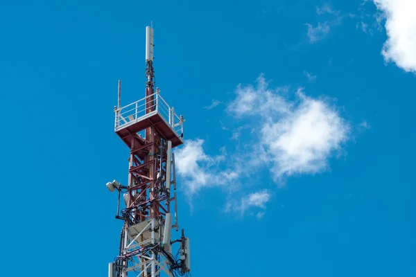 communication tower over blue sky with single cloud