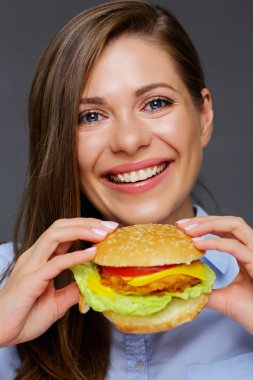 Lezzetli burger tutarak ve kameraya, Fast food kavramı seyir gülümseyen güzel kadın 