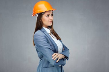 Kadın Oluşturucusu mühendis kask ayakta gri duvar karşı çapraz kolları olan