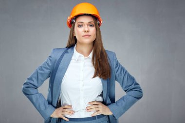 Giyen kadın builder mimar korumak gri arka plan üzerinde poz süre kask bakmak başarılı ve kendinden emin 