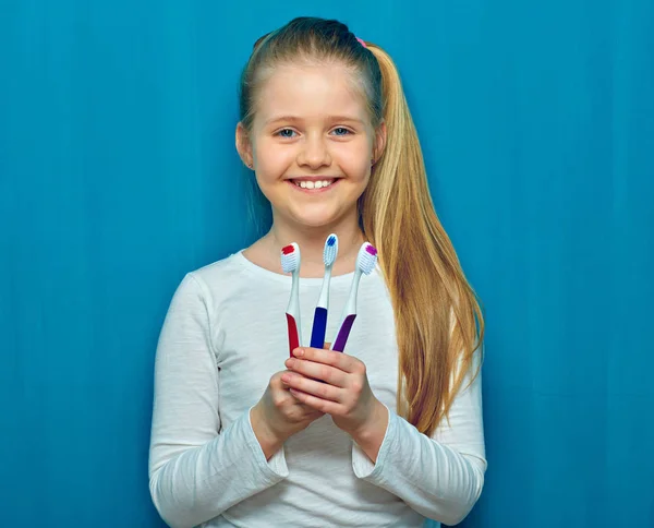 Sonriente Niña Sosteniendo Tres Cepillo Dientes Sobre Fondo Pared Azul —  Fotos de Stock