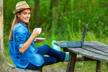 kahve içme ve Bahçe içinde laptop ile çalışan genç kadın 