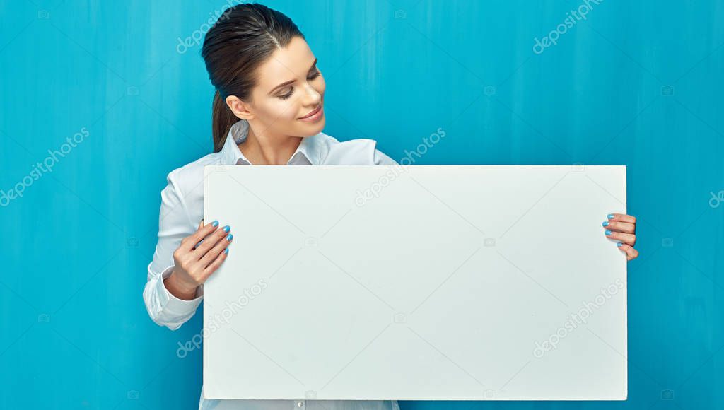 smiling woman holding big white empty banner on blue wall background  