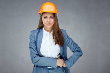 kask ve gri arka plan üzerinde poz takım elbise giyen başarılı ve kendinden emin bir kadın builder mimar korumak