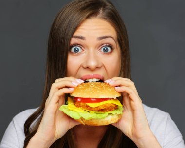 Büyük hamburger gri duvar arka planda, lokanta kavramı ısırma genç kadın portresi 