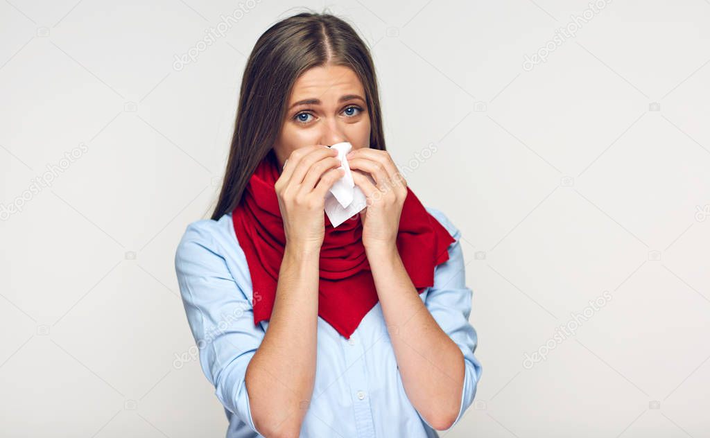 Sick woman in red scarf and blue shirt using tissue