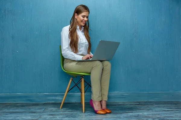 Uśmiecha Się Kobieta Pracująca Laptopa Siedząc Krześle Tle Ściany Niebieskie — Zdjęcie stockowe