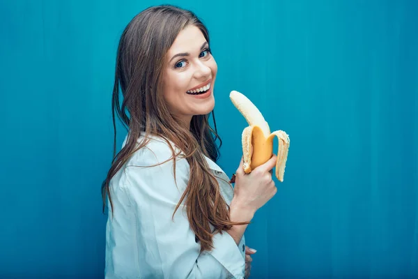 Mulher Sorrindo Comendo Banana Enquanto Posando Contra Fundo Parede Azul — Fotografia de Stock