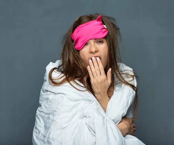 Portrait of yawning woman with blanket and blindfold eyes mask for sleep, wake up concept