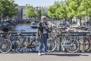 Amsterdam, Hollanda - 01.2011 olabilir: Bir fotoğrafçı bir boru bir köprüde bir şehir kanal üzerinde ışıklar