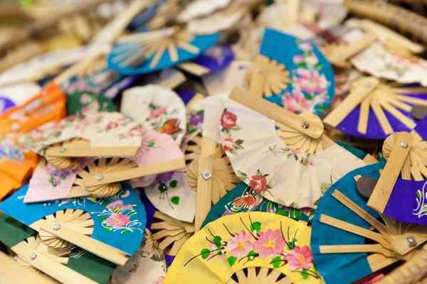 Small colored and handmade fans for sale in a factory in Thailand.