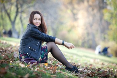 Güzel genç kadın parkta sonbahar güneşli günde iyi vakit geçiriyor.