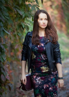 Güzel genç kadın parkta sonbahar güneşli günde iyi vakit geçiriyor.