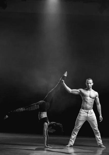 A man and a woman performing a contemporary dance pose on a stage.