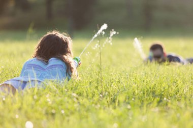 Birbirlerini takip ve su silahlarla oynayan bir çayır ar gün batımı oynak genç bir çift.