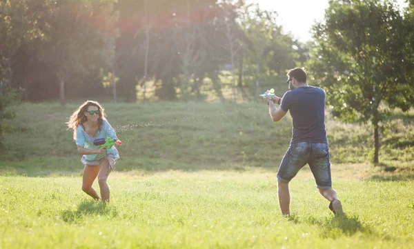 Playful Young Couple Chasing Each Other Playing Water Guns Meadow — Stock Photo, Image