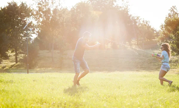 Playful Young Couple Chasing Each Other Playing Water Guns Meadow — Stock Photo, Image