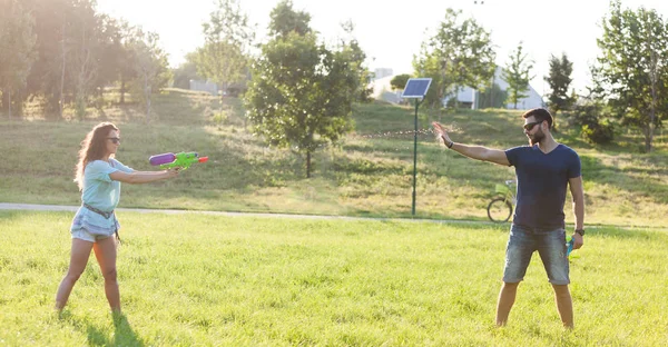 Playful Young Couple Chasing Each Other Playing Water Guns Meadow — Stock Photo, Image