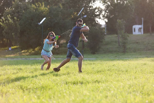 Playful Young Couple Chasing Each Other Playing Water Guns Meadow — Stock Photo, Image