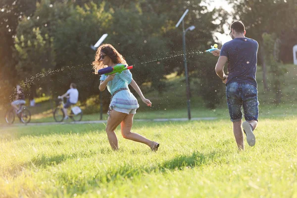 Playful Young Couple Chasing Each Other Playing Water Guns Meadow — Stock Photo, Image