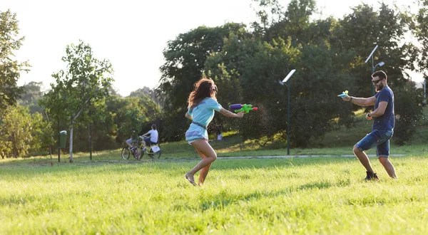 Playful Young Couple Chasing Each Other Playing Water Guns Meadow — Stock Photo, Image