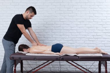 Evde bir fizyoterapist tarafından masaj sezyonu geçirilen genç bir kadın..