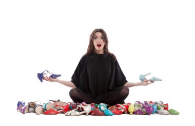 Beyaz arka planda izole edilmiş genç bir kadın. Bir sürü farklı beden ve renkte ayakkabısı var..