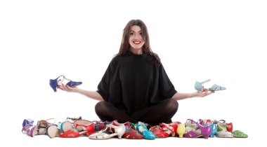 Beyaz arka planda izole edilmiş genç bir kadın. Bir sürü farklı beden ve renkte ayakkabısı var..