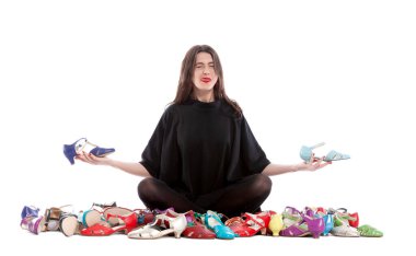 Beyaz arka planda izole edilmiş genç bir kadın. Bir sürü farklı beden ve renkte ayakkabısı var..