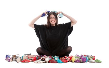 Beyaz arka planda izole edilmiş genç bir kadın. Bir sürü farklı beden ve renkte ayakkabısı var..