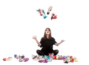 Beyaz arka planda izole edilmiş genç bir kadın. Bir sürü farklı beden ve renkte ayakkabısı var..