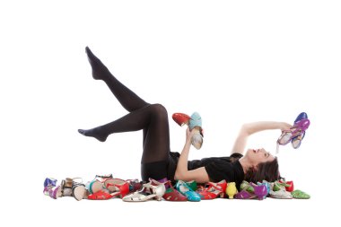 Beyaz arka planda izole edilmiş genç bir kadın. Bir sürü farklı beden ve renkte ayakkabısı var..