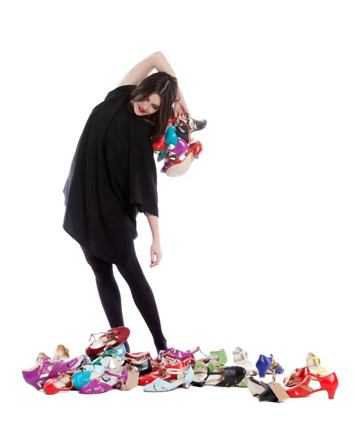多くのサイズと色の靴がたくさんある白い背景に隔離された若い女性 — ストック写真